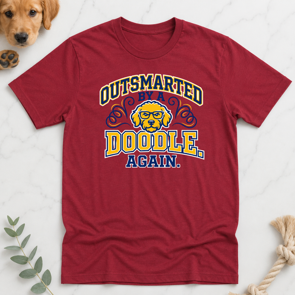Red t-shirt with 'Outsmarted by a Doodle Again' graphic on a white background
